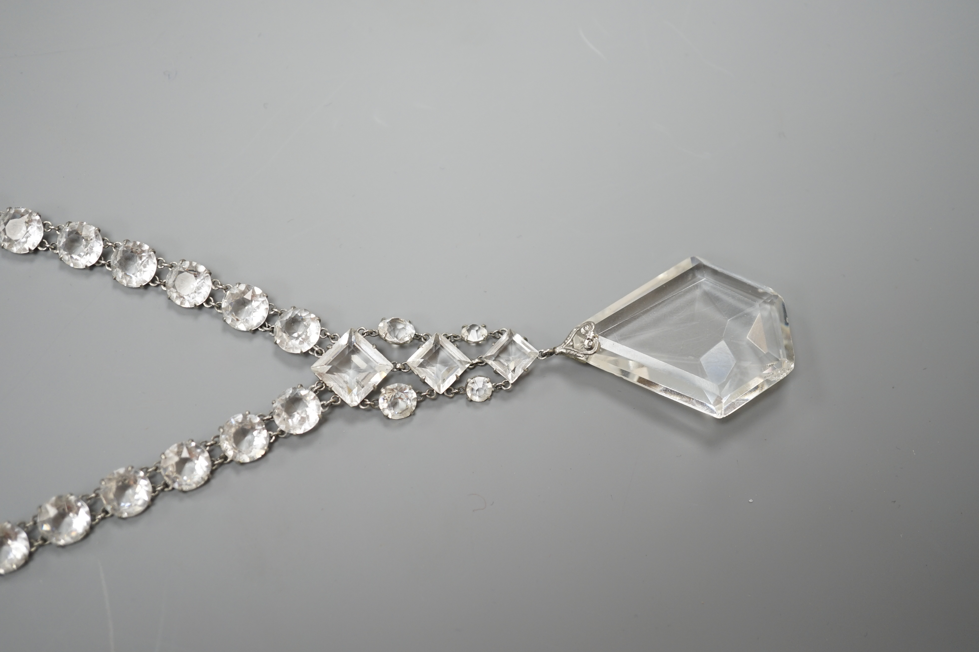 An early 20th century ornate white metal and facet cut paste set drop necklace, overall approx. 44cm.